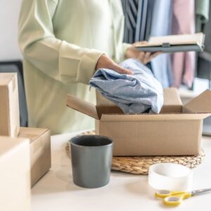 person packing clothes into cardboard boxes