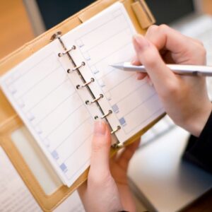 person writing in schedule