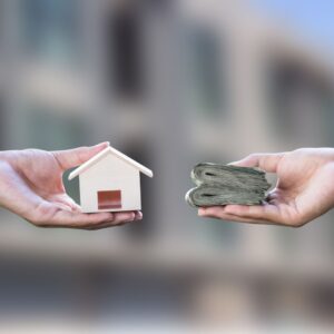 person exchanges cash for wooden house model