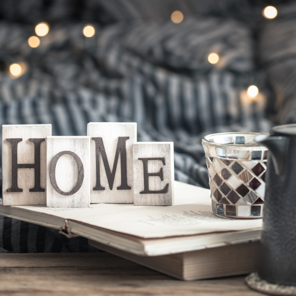 Cozy home decor including blanket, wooden blocks spelling "home" and a candle.